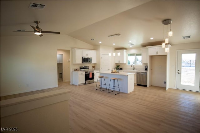 kitchen with visible vents, a center island, stainless steel appliances, light countertops, and white cabinetry