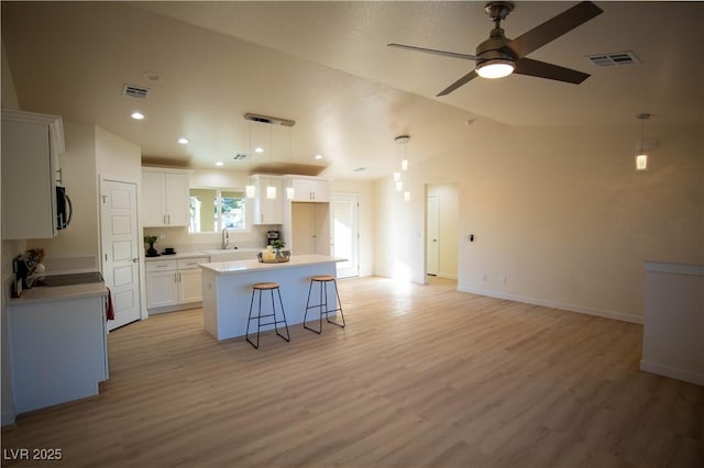 kitchen featuring white cabinets, light countertops, a kitchen island, and visible vents