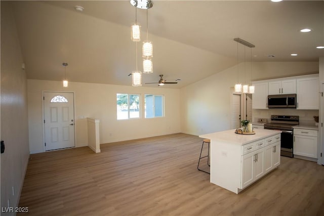 kitchen with lofted ceiling, white cabinets, light countertops, and appliances with stainless steel finishes