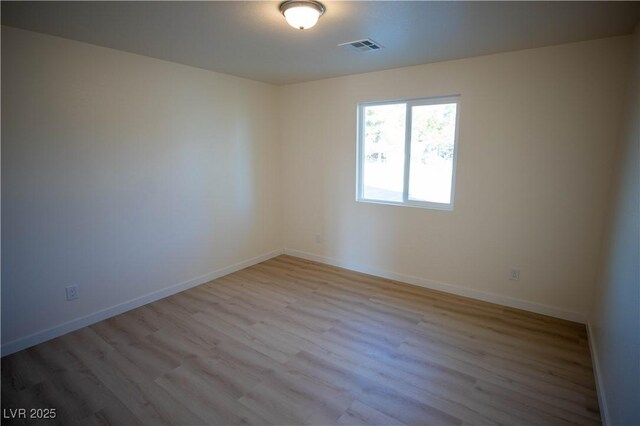 empty room featuring light wood-style flooring, visible vents, and baseboards