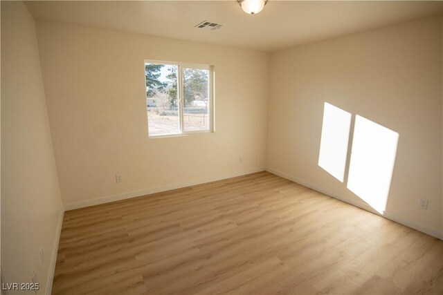 empty room featuring light wood finished floors, visible vents, and baseboards