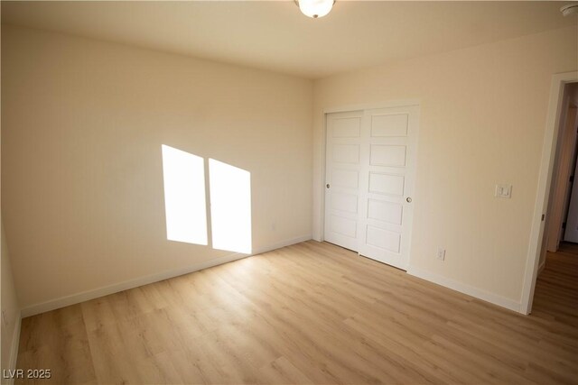 unfurnished bedroom with a closet, light wood-style flooring, and baseboards