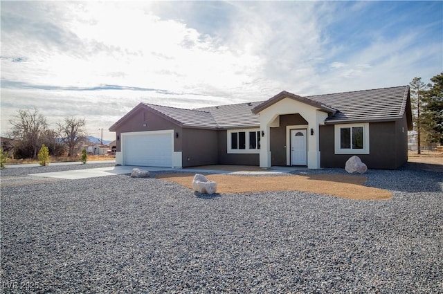 single story home featuring a garage, concrete driveway, stucco siding, and a tiled roof