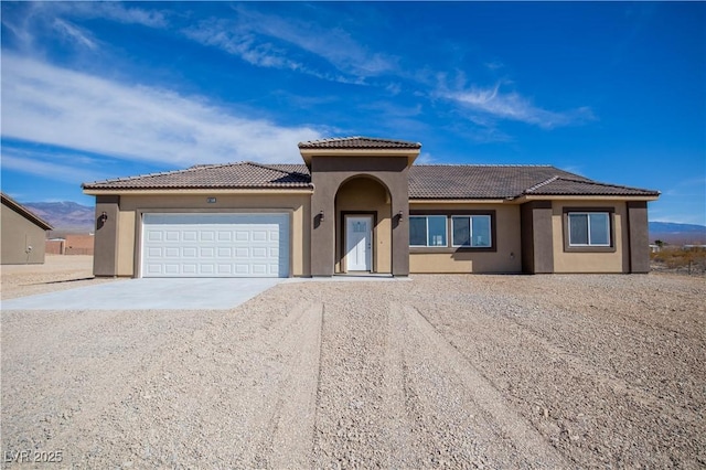 view of front of home featuring a garage, driveway, a tile roof, and stucco siding