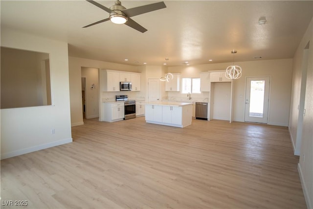 kitchen featuring white cabinets, open floor plan, light countertops, appliances with stainless steel finishes, and a center island