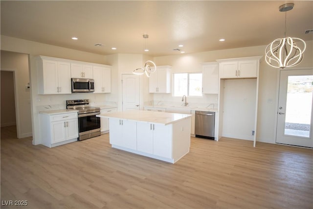 kitchen with pendant lighting, light countertops, appliances with stainless steel finishes, white cabinets, and a kitchen island