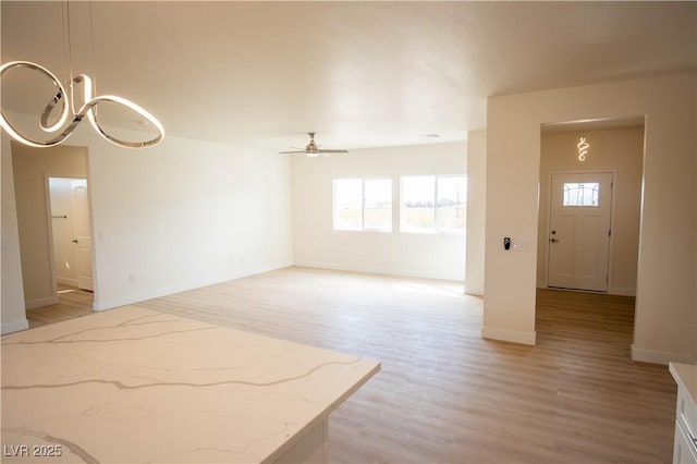 5821 Genoa Ave, Pahrump, NV 89060 - unfurnished living room featuring light wood-type flooring, a ceiling fan, baseboards, and a healthy amount of sunlight