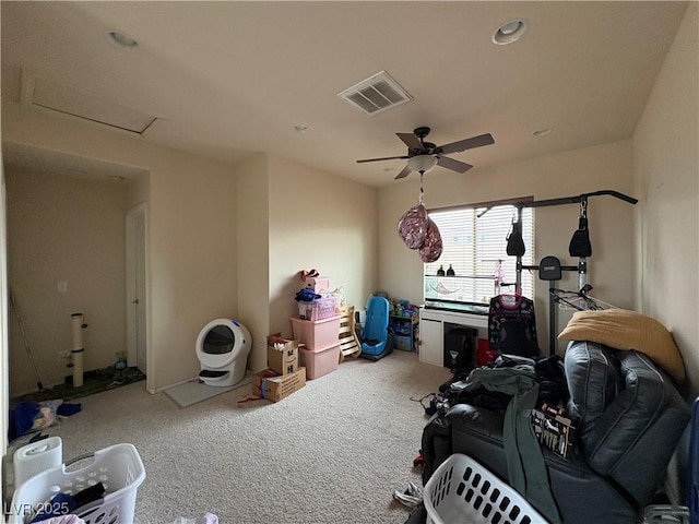 exercise area featuring visible vents, carpet floors, attic access, and a ceiling fan