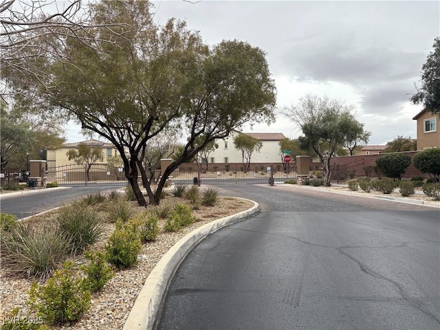 view of road featuring traffic signs, a gate, curbs, and a gated entry