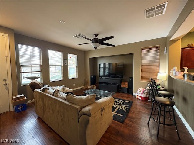 living area with visible vents, dark wood-type flooring, and ceiling fan