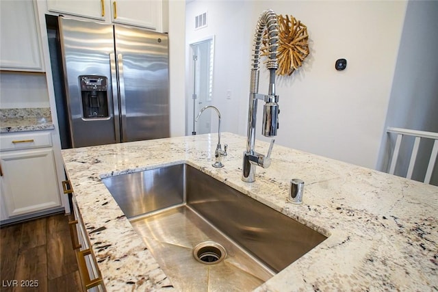 kitchen featuring sink, dark hardwood / wood-style floors, stainless steel refrigerator with ice dispenser, light stone countertops, and white cabinets