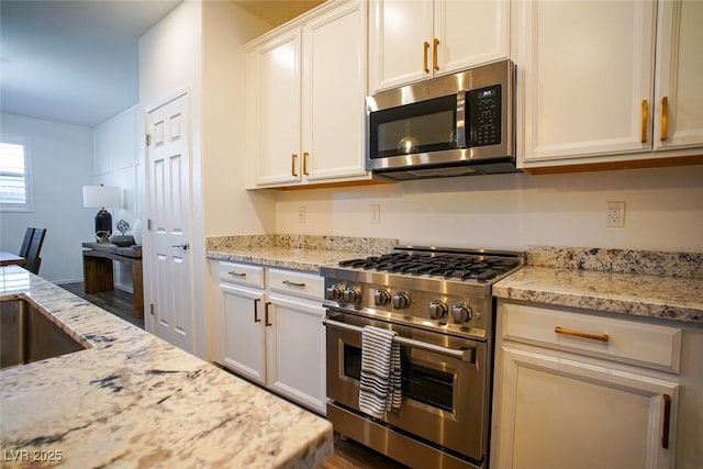 kitchen with white cabinetry, appliances with stainless steel finishes, and light stone counters