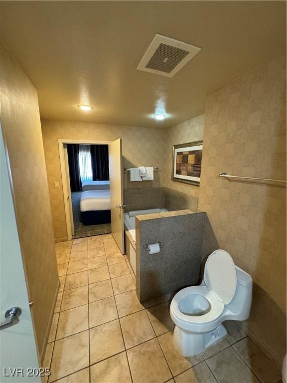 bathroom featuring tile patterned flooring, a tub, and toilet