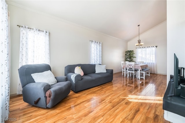 living room featuring an inviting chandelier, hardwood / wood-style floors, crown molding, and vaulted ceiling