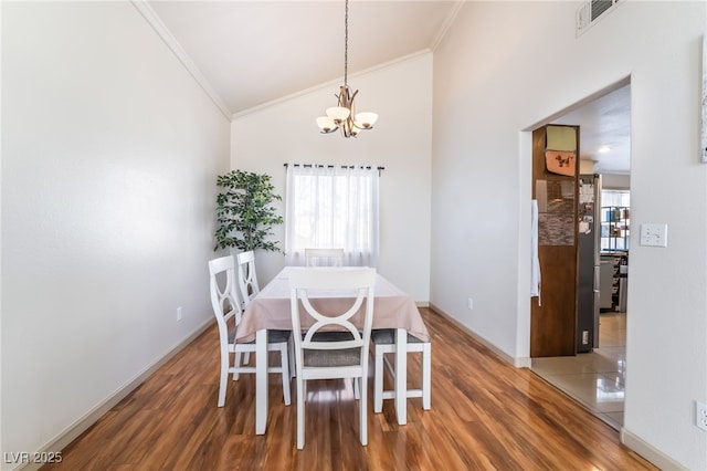 dining space featuring crown molding, dark wood-type flooring, a notable chandelier, and a healthy amount of sunlight