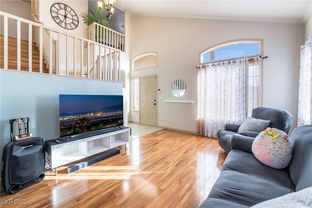 living room featuring an inviting chandelier, hardwood / wood-style floors, crown molding, and a towering ceiling