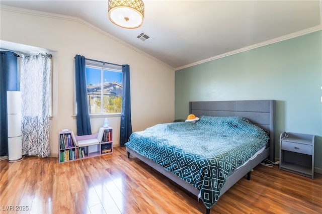 bedroom with ornamental molding, lofted ceiling, and hardwood / wood-style floors