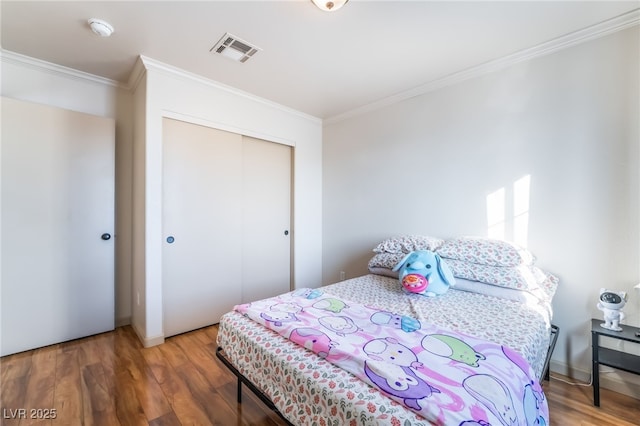 bedroom with crown molding, dark hardwood / wood-style floors, and a closet