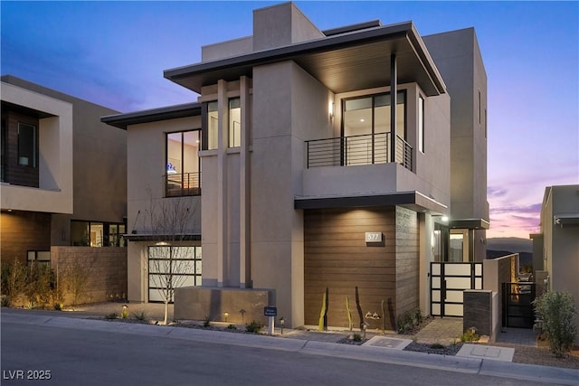 view of front of house with fence, a balcony, and stucco siding