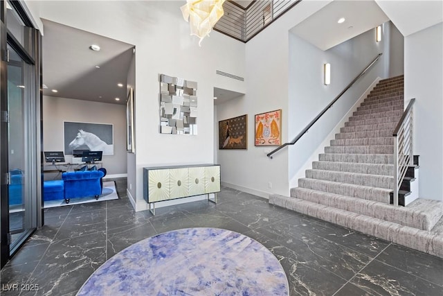 foyer with marble finish floor, baseboards, and stairs