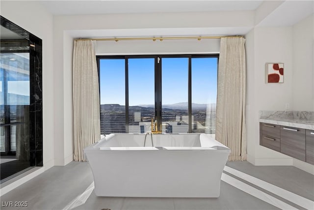 bathroom featuring a soaking tub, baseboards, a mountain view, and vanity