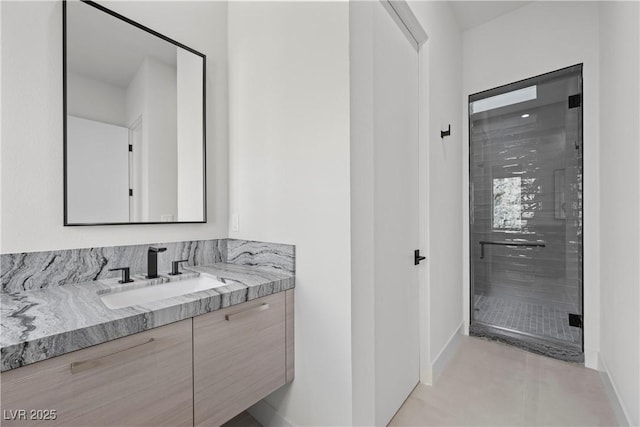 bathroom with baseboards, a stall shower, vanity, and tile patterned floors