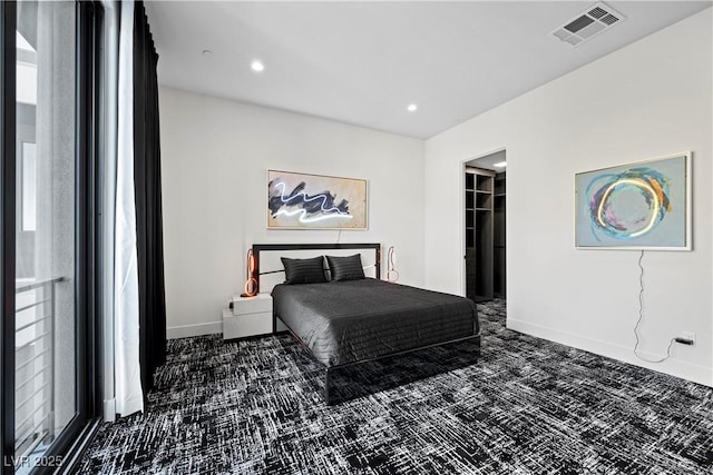 carpeted bedroom featuring recessed lighting, a walk in closet, visible vents, and baseboards