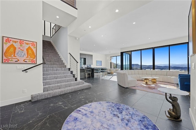 living area with recessed lighting, a mountain view, baseboards, and stairs