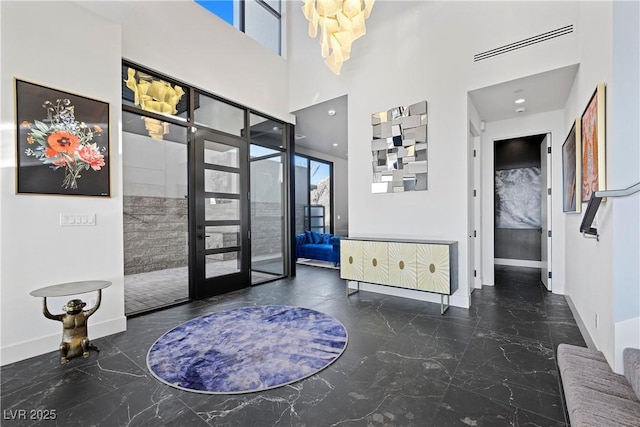 foyer entrance with a high ceiling, visible vents, baseboards, marble finish floor, and french doors