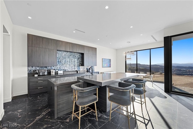 kitchen with marble finish floor, a mountain view, backsplash, and modern cabinets