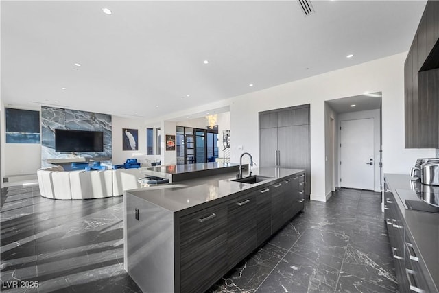 kitchen featuring a sink, visible vents, marble finish floor, modern cabinets, and a large island with sink