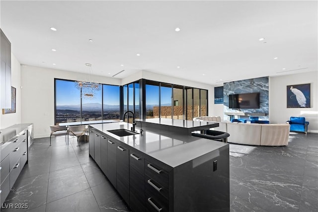 kitchen with recessed lighting, modern cabinets, a sink, and a center island with sink