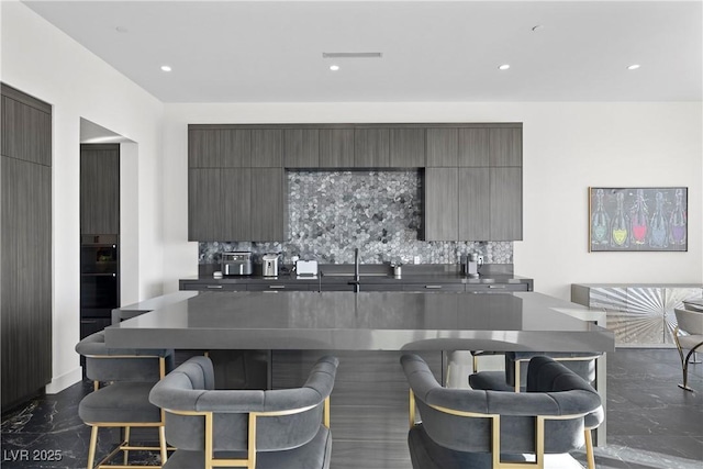 kitchen with dark countertops, marble finish floor, decorative backsplash, and modern cabinets