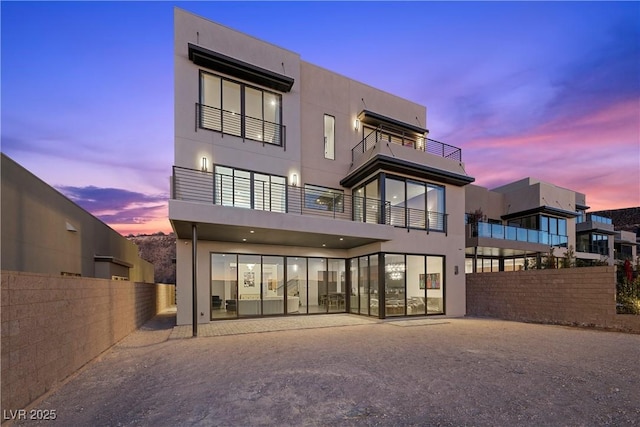 rear view of property featuring fence and stucco siding