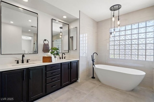 bathroom with vanity, tile patterned floors, tile walls, and a bathing tub