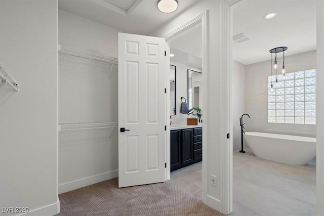 bathroom with a washtub, vanity, and tile patterned flooring