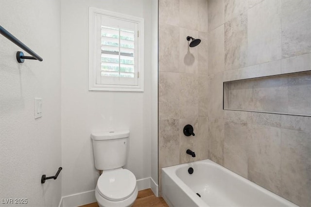 bathroom featuring tiled shower / bath combo, wood-type flooring, and toilet