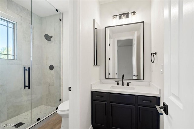 bathroom with vanity, hardwood / wood-style floors, an enclosed shower, and toilet