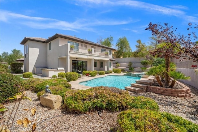 back of house with a fenced in pool, a balcony, and ceiling fan