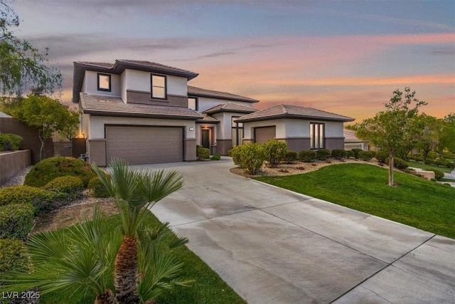 prairie-style home featuring a garage and a lawn