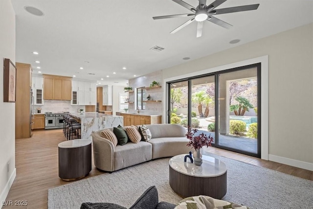 living room with ceiling fan and light hardwood / wood-style flooring