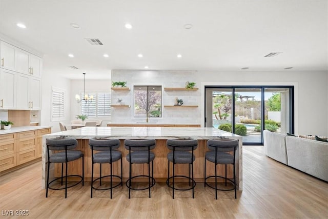 kitchen with a spacious island, decorative light fixtures, a breakfast bar area, and white cabinets