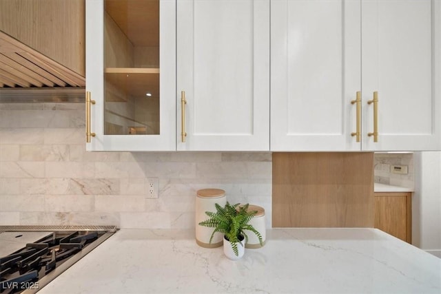 kitchen featuring stovetop, decorative backsplash, and white cabinets