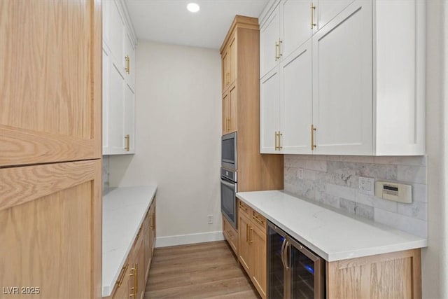 kitchen with white cabinetry, wine cooler, light stone countertops, light hardwood / wood-style floors, and stainless steel oven