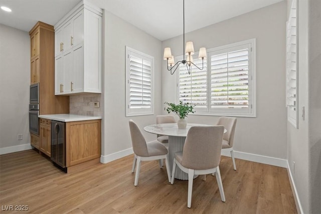 dining area featuring wine cooler, a chandelier, and light hardwood / wood-style flooring