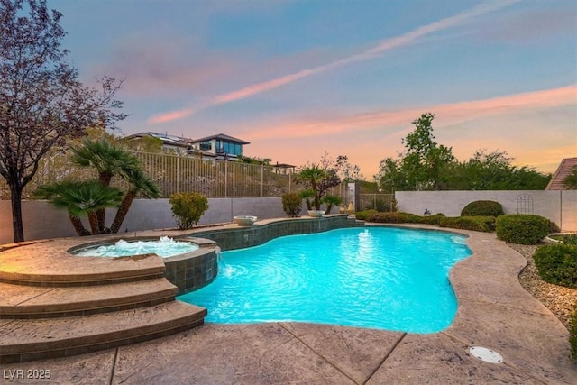 pool at dusk featuring an in ground hot tub and pool water feature