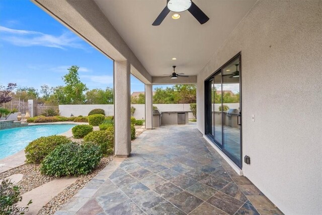 view of patio with ceiling fan, an outdoor kitchen, and a fenced in pool