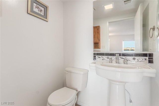 bathroom featuring toilet and decorative backsplash