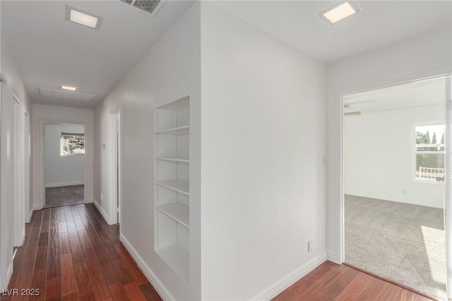 hall featuring built in shelves, plenty of natural light, and dark wood-type flooring