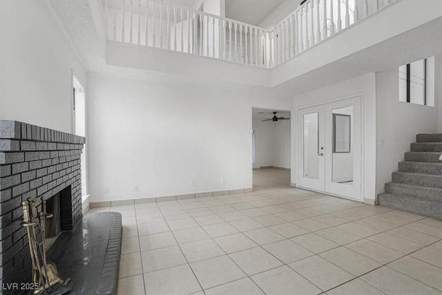 unfurnished living room with a fireplace, a wealth of natural light, a high ceiling, and light tile patterned floors